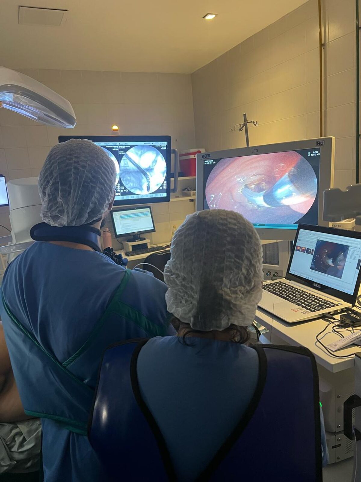 Equipe médica acompanhando procedimento de CPRE nos monitores